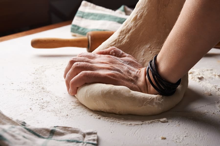 Hands kneading wheat dough on a floured board
