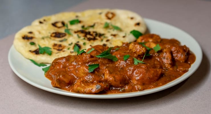 Kulcha bread beside a bowl of curry