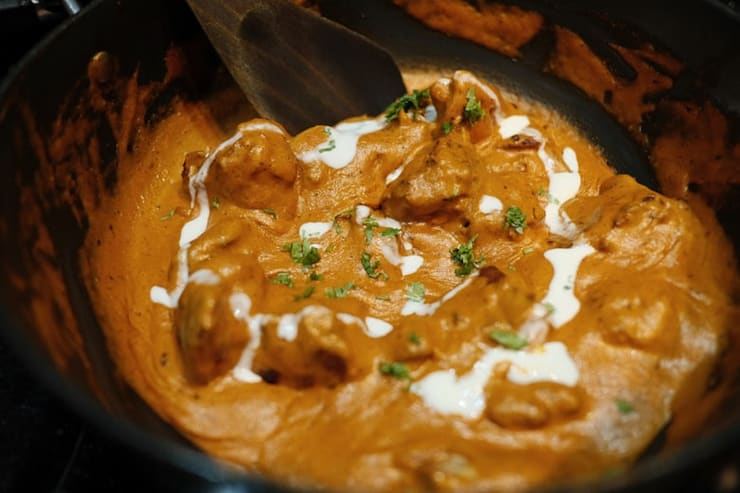 Butter chicken, thick and glossy in a black pan