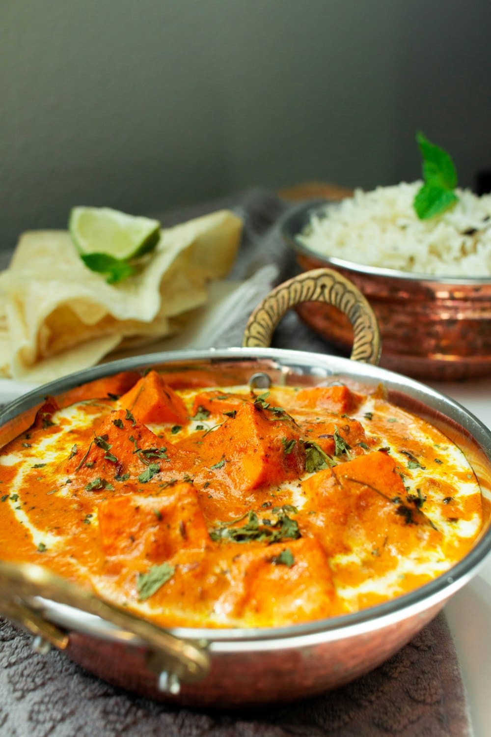 Butter chicken in a copper karahi with papad and rice
